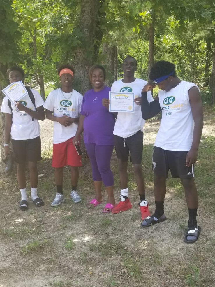 Youth recognition moment with certificates and mentors outdoors