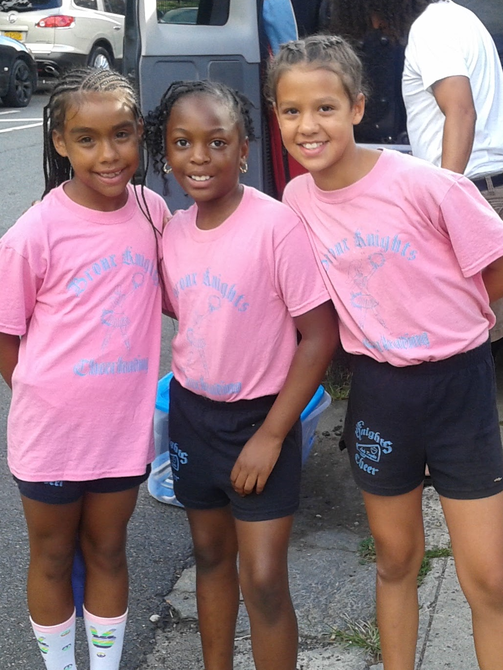 Three youth program participants standing together in team shirts